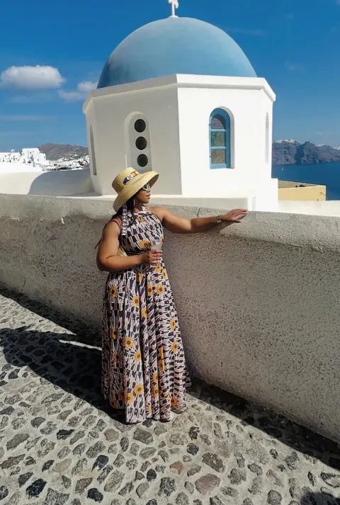 A traveller beside a white church with a blue dome in Santorini