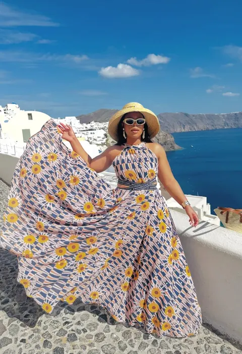 A traveller in a flowing dress overlooking the Santorini caldera