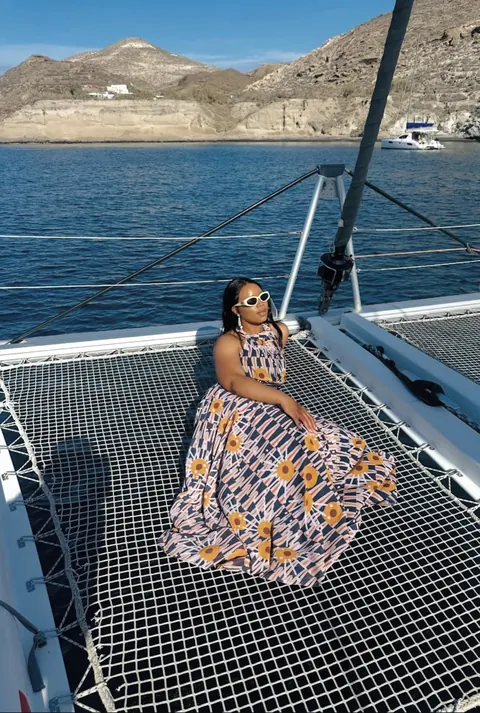 A traveller relaxing on the net of a catamaran in a sheltered bay