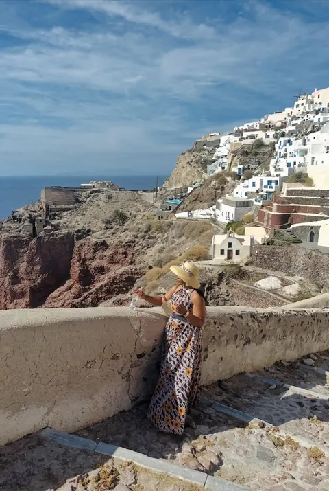 A traveller overlooking the whitewashed cliffside buildings of Santorini