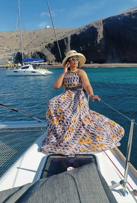 A traveller on a catamaran beside volcanic cliffs and blue water