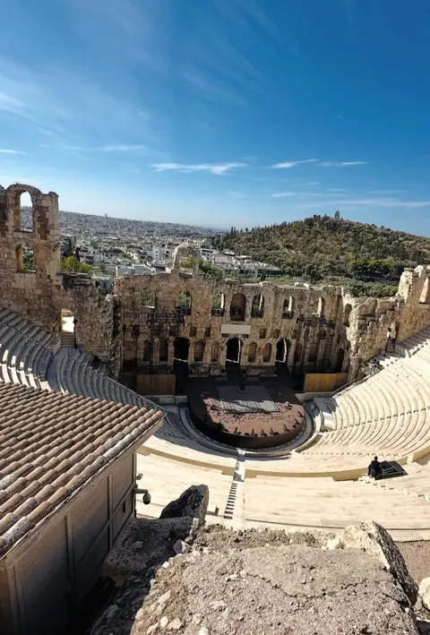 Ancient stone theatre with the city of Athens stretching beyond