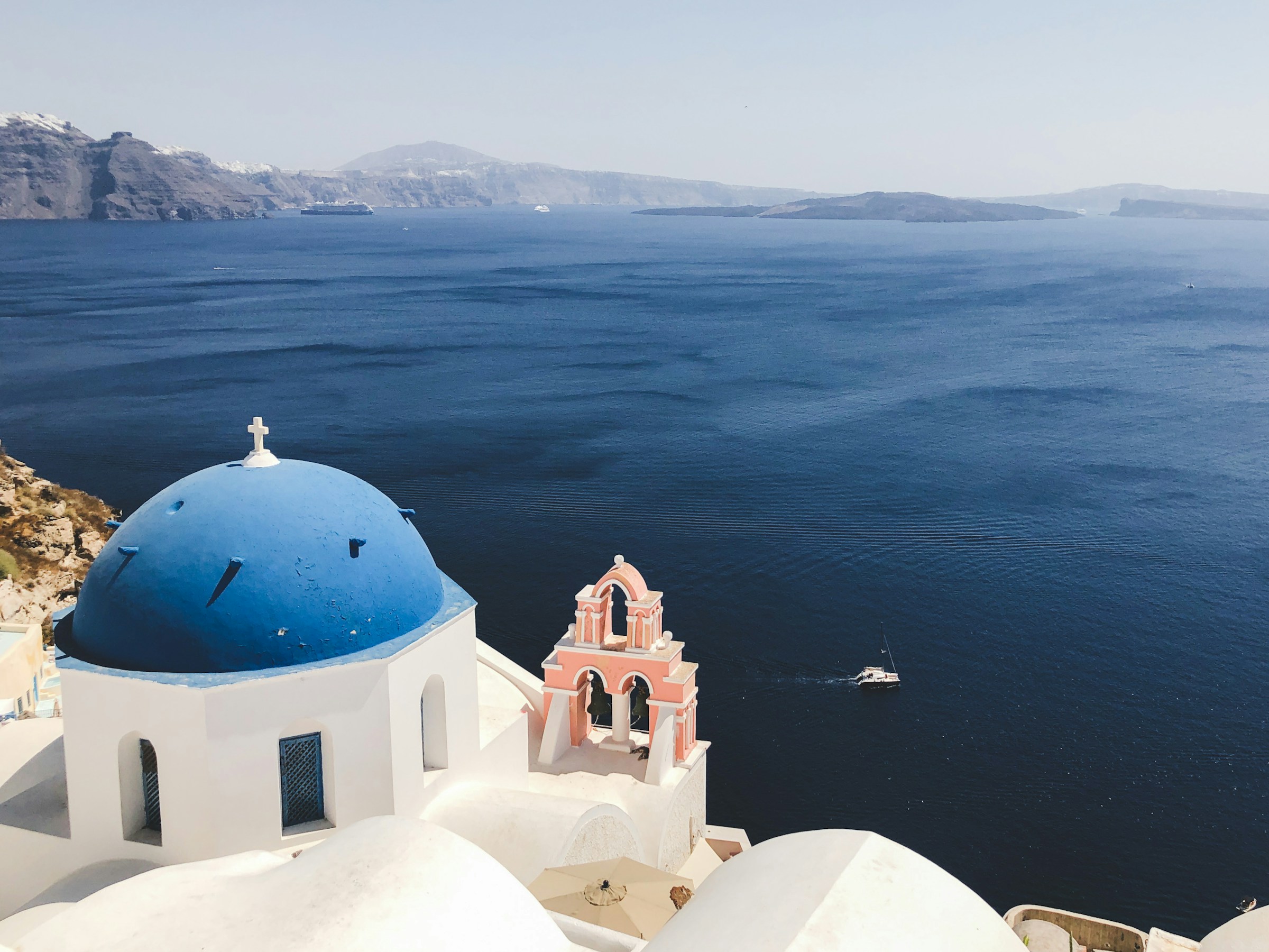 White church with a blue dome overlooking the Santorini caldera