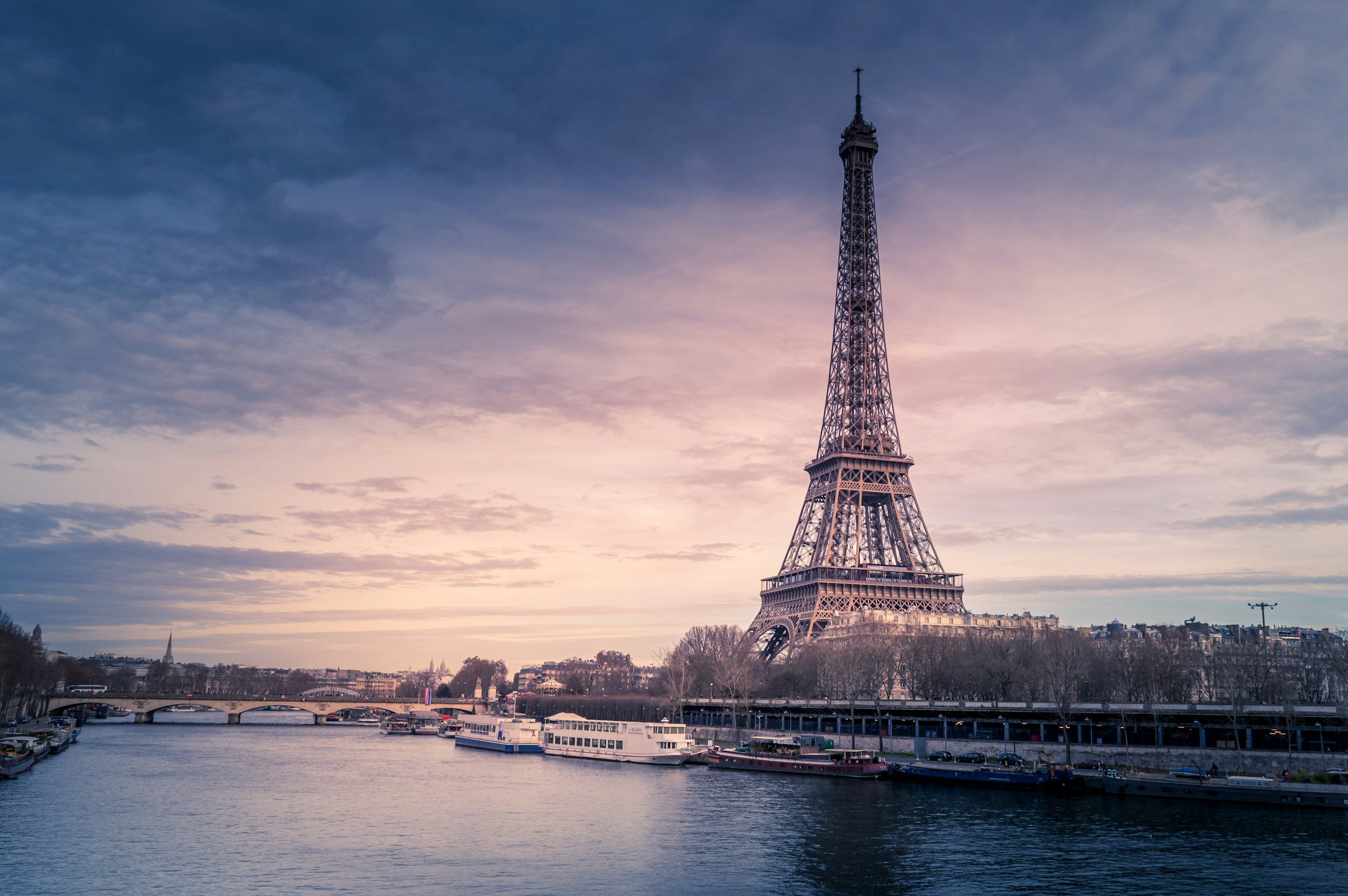 Eiffel Tower overlooking the Seine beneath a pastel sunset sky