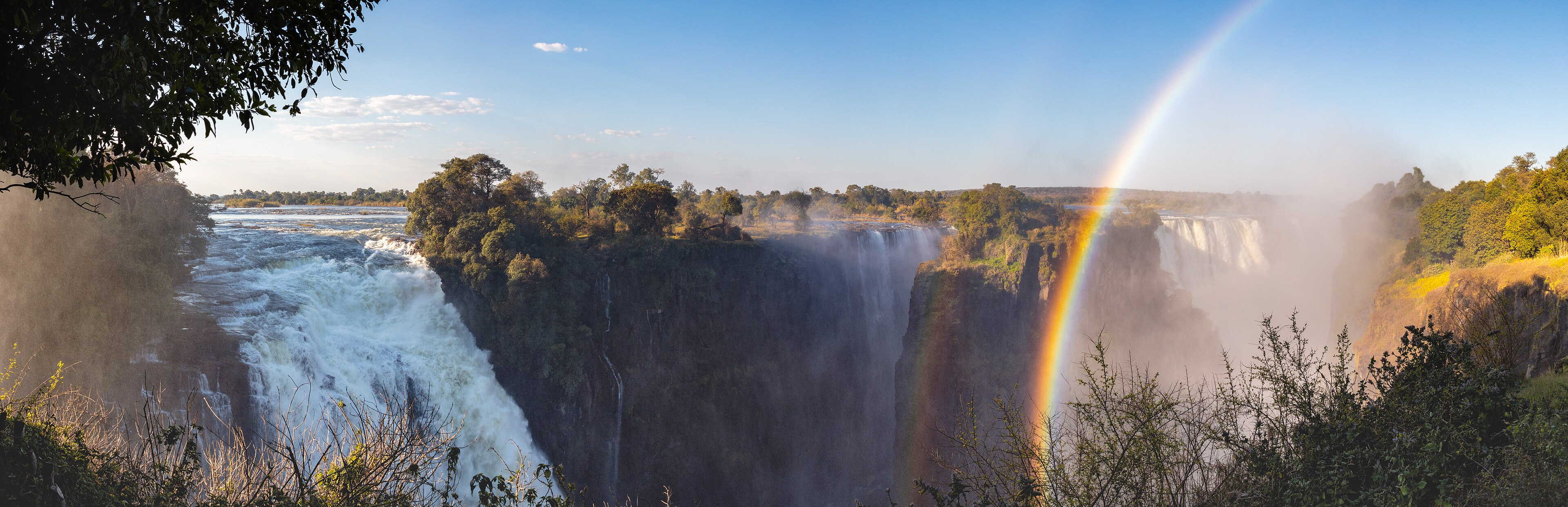 Panoramic Victoria Falls with a bright rainbow above the Zambezi River